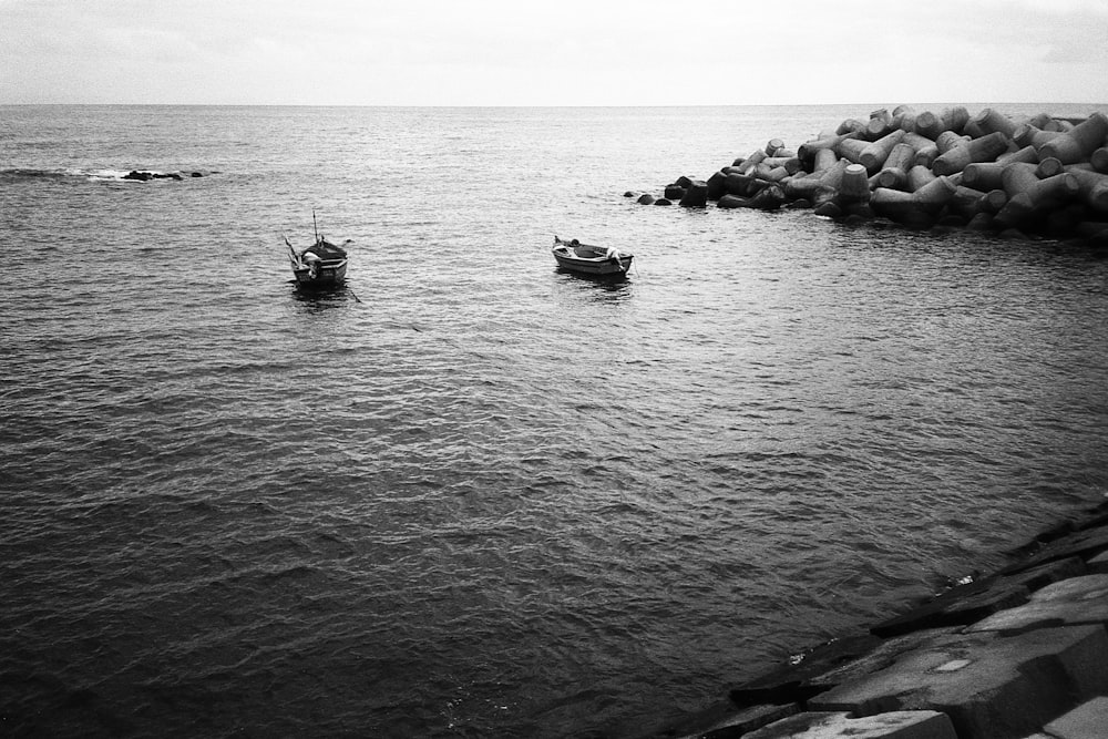 grayscale photo of two paddle boats near shore