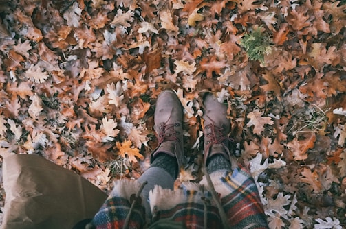 A point-of-view shot of a layered autumn outfit with cozy knits and vintage boots.