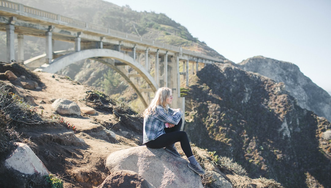 woman wearing plaid shirt sitting on rock