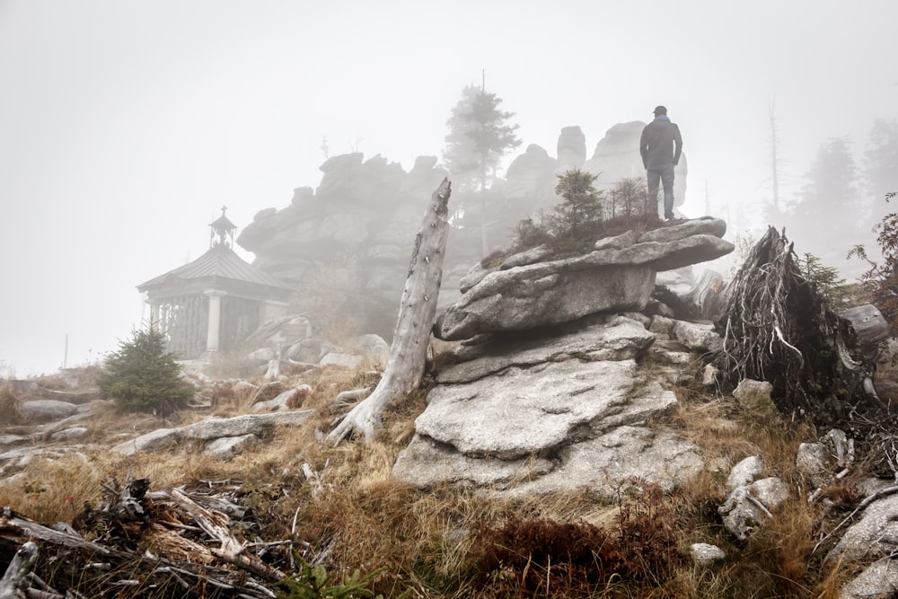 Persona in piedi sulla formazione rocciosa con le nebbie