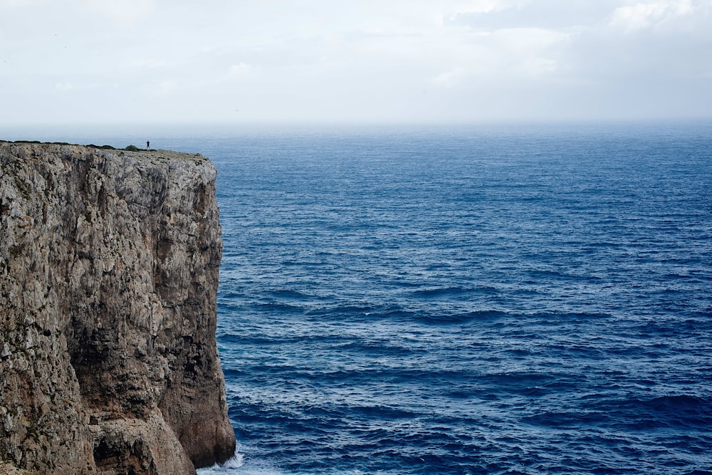 mountain cliff surrounded by body of water during daytime