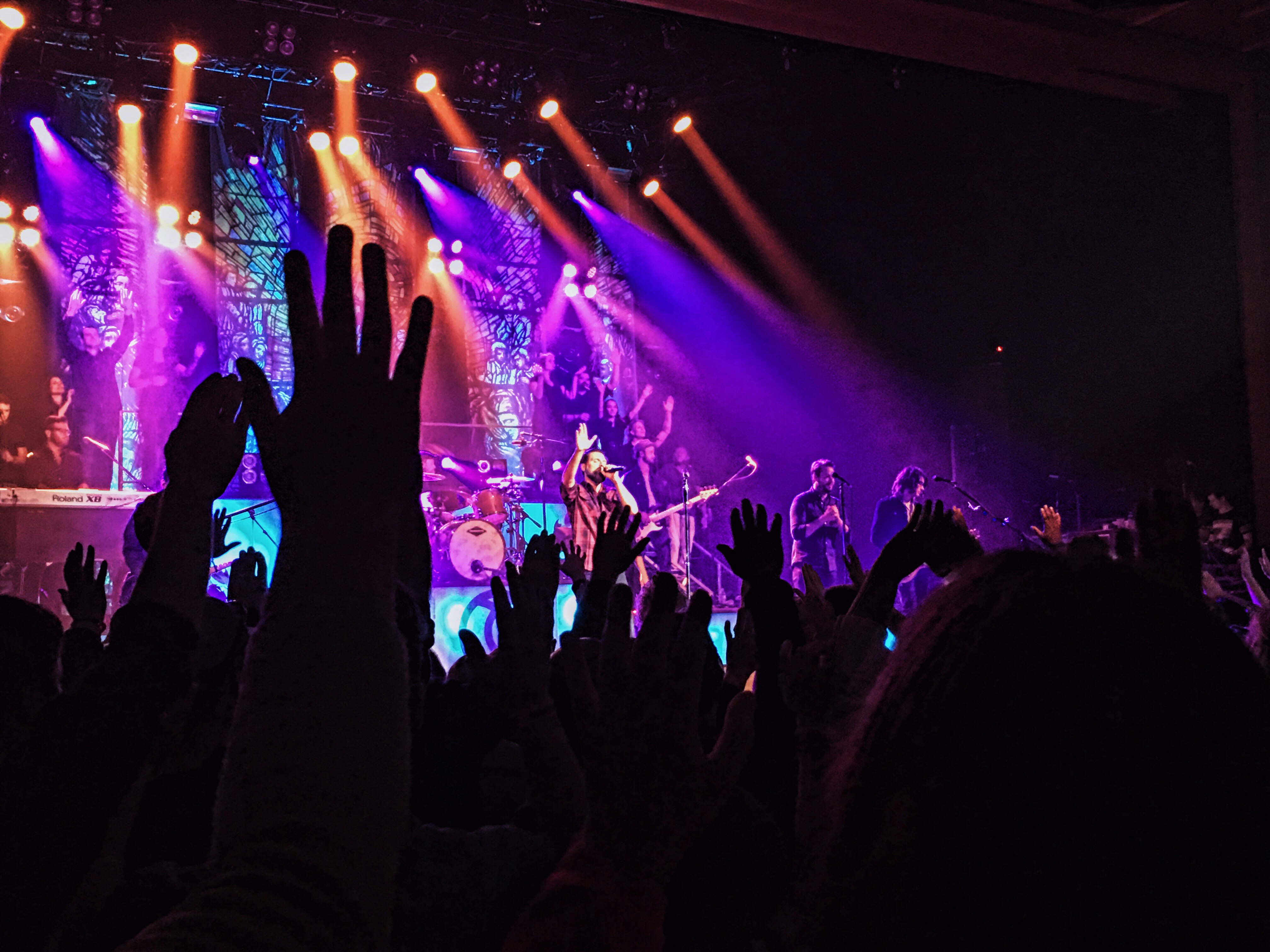 people raising their hands in front of stage