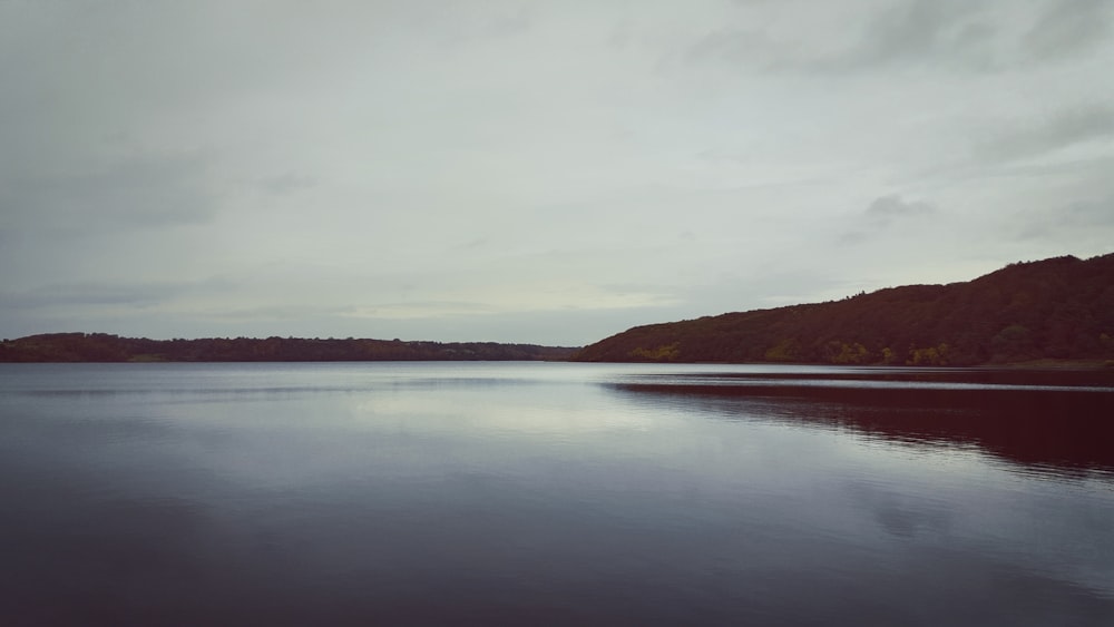 body of water near mountain during daytime