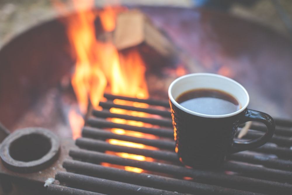 black ceramic mug near fire