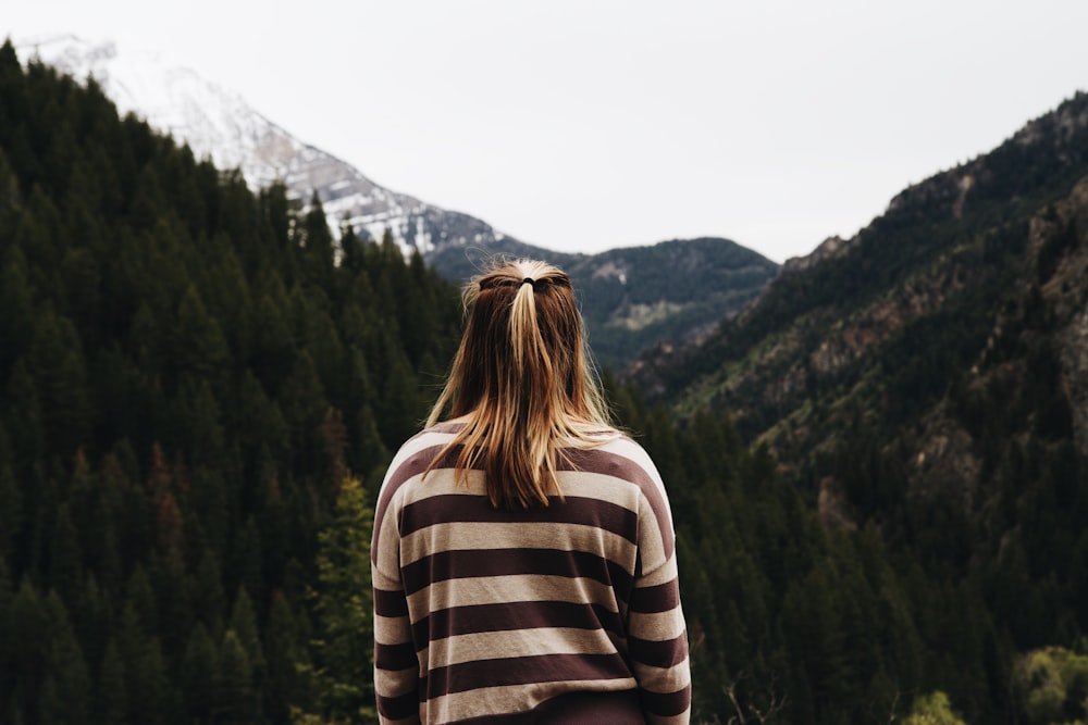 donna che indossa una camicia a maniche lunghe a righe di fronte alle montagne
