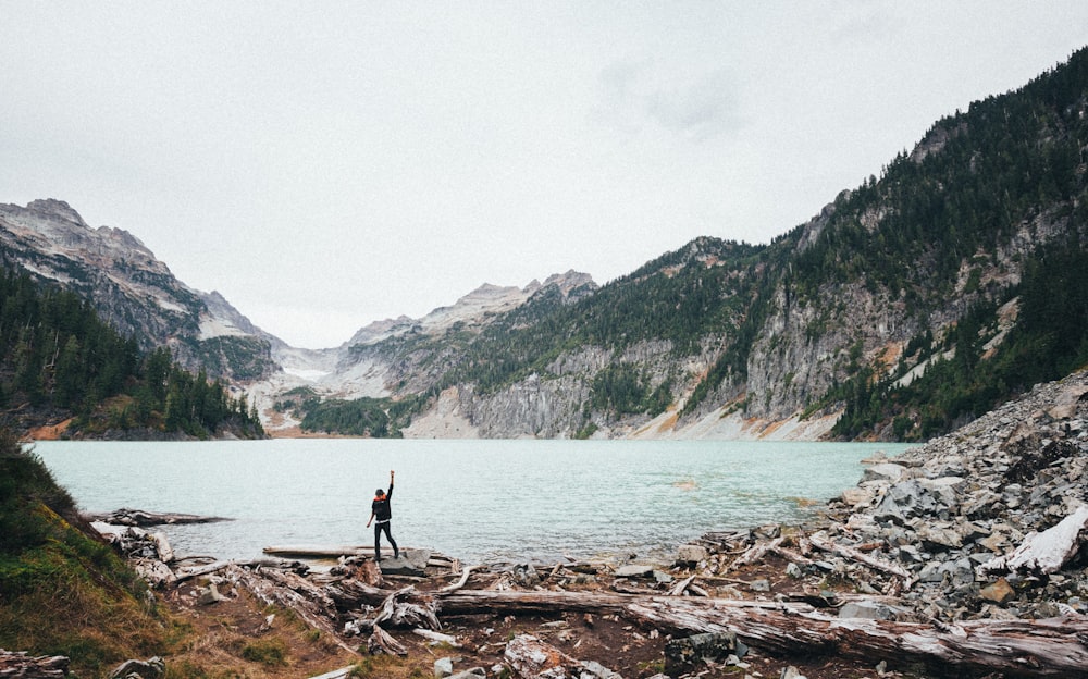 man raising its hand near body of water