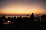 Guests enjoying a sunset view on the beach, with containers in the background enhancing the atmosphere.