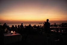 Guests enjoying a sunset view on the beach, with containers in the background enhancing the atmosphere.