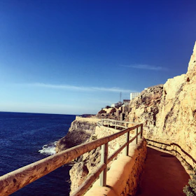 Scenic coastal hiking path with blue sea and rugged cliffs under a clear sky in northern Morocco.