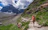A happy woman hiking on a mountain trail with a well-fitted backpack.