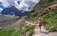 A happy woman hiking on a mountain trail with a well-fitted backpack.