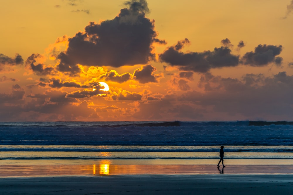 personne sur le rivage de la plage au coucher du soleil