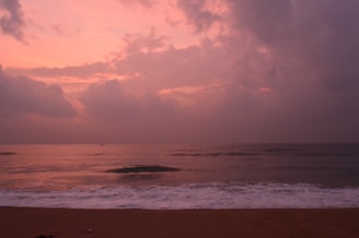 A serene coastal scene with soft waves gently touching a sandy shore under a pastel sky.