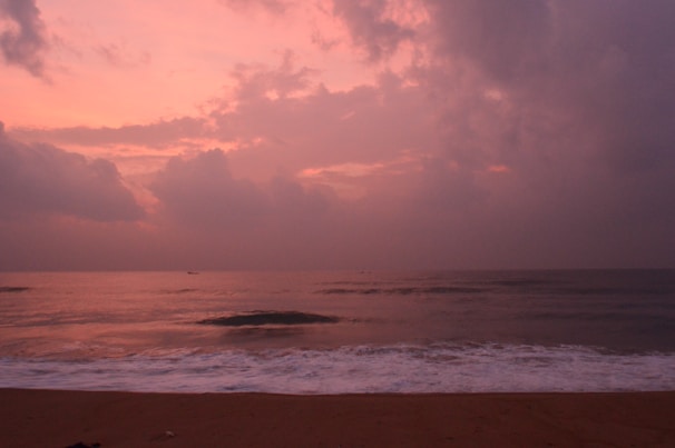 A serene coastal scene with soft waves gently touching a sandy shore under a pastel sky.