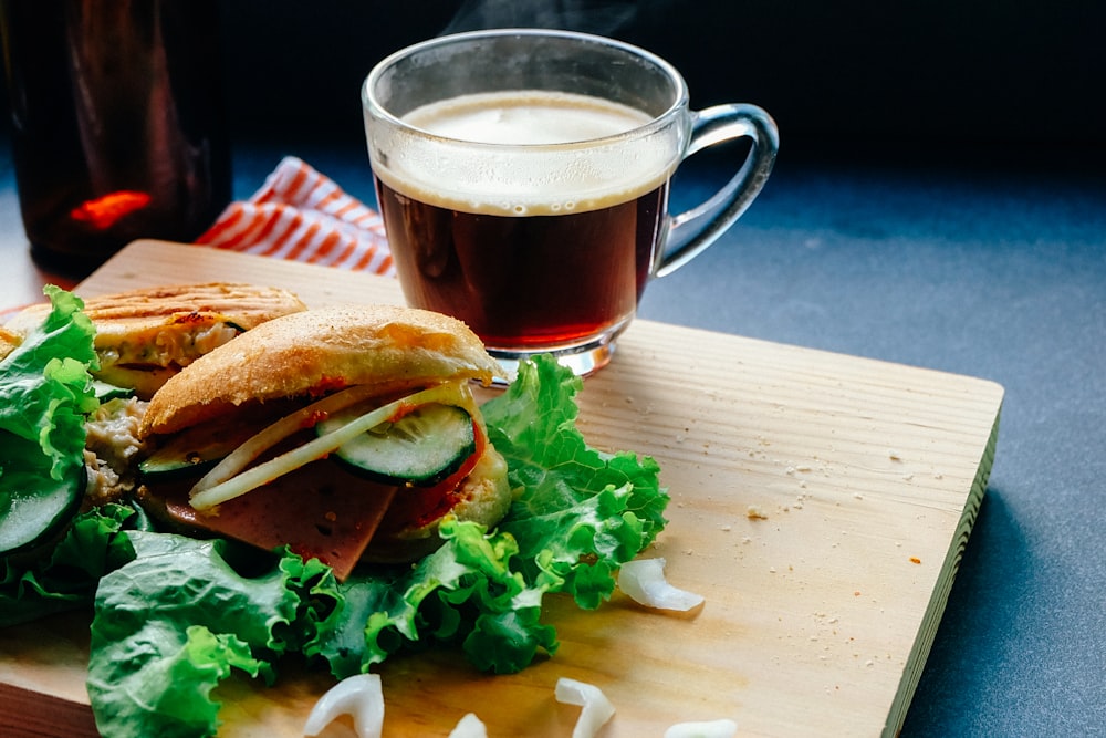 Brötchen mit Gemüse neben Klarglasbecher auf Holztablett