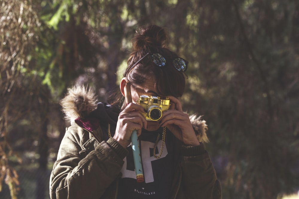 woman in black jacket holding green and white camera
