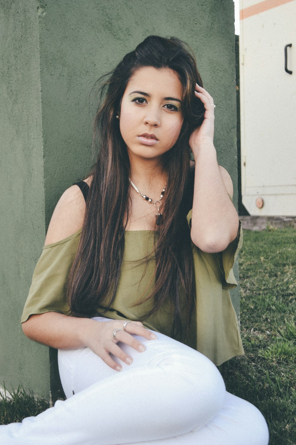 woman in green off-shoulder top holding her hair pose