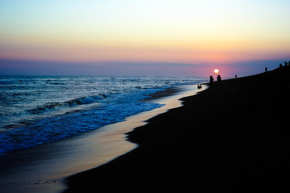 photography of silhouette of people on seashore