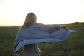 A wide shot of a model wearing a classic denim jacket and boots, standing against a sunset-lit ranch backdrop.