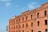 A large brick building with multiple arched windows, showcasing traditional architectural style. A sign on the building indicates it's a visitor center. The sky is clear with a few clouds, providing a bright and inviting atmosphere.