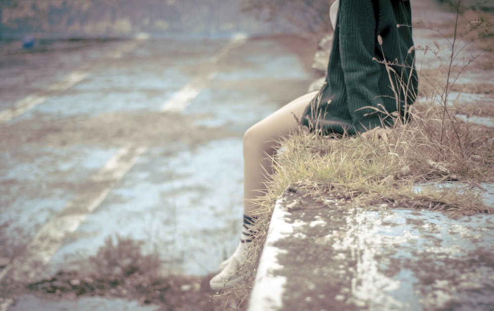 woman sitting on concrete barrier