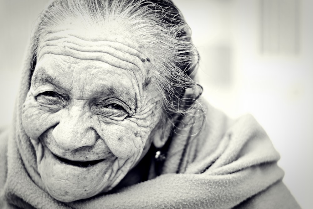 Elderly woman with care worn face laughs in black and white photo