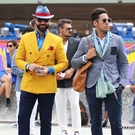 two man wearing yellow and grey suit jacket standing close together