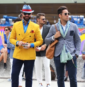 two man wearing yellow and grey suit jacket standing close together