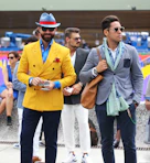 two man wearing yellow and grey suit jacket standing close together