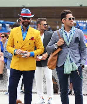 two man wearing yellow and grey suit jacket standing close together