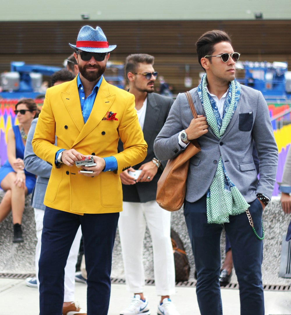 two man wearing yellow and grey suit jacket standing close together