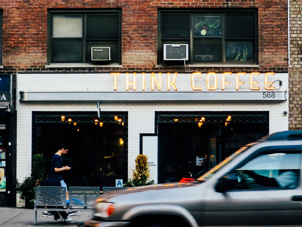 gray car at the front of Think Coffee shop