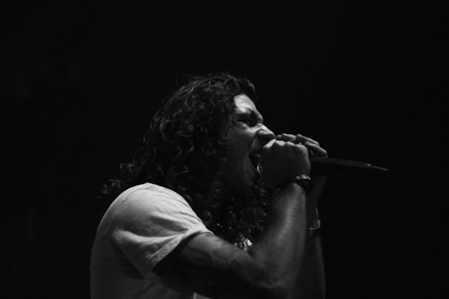 Close-up of a young Afro-Colombian artist passionately singing into a microphone during a live performance.