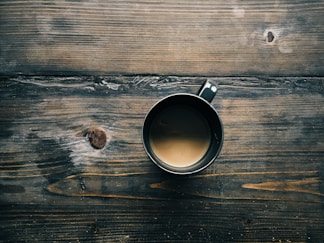 gray cup with brown liquid inside on top of table
