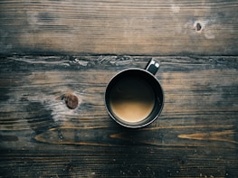 gray cup with brown liquid inside on top of table