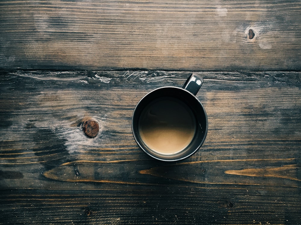 gray cup with brown liquid inside on top of table