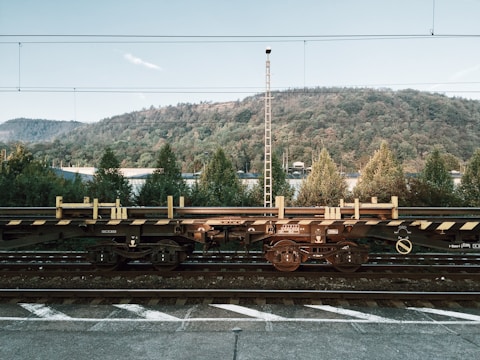 Rail freight cars loaded with large industrial parts moving through a scenic countryside.