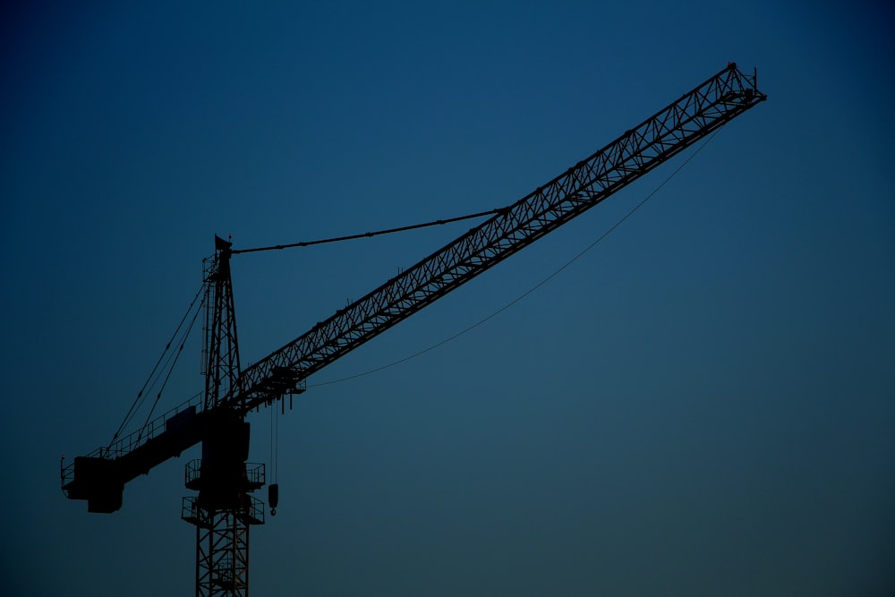 Torre de grúa de metal negro bajo cielo azul