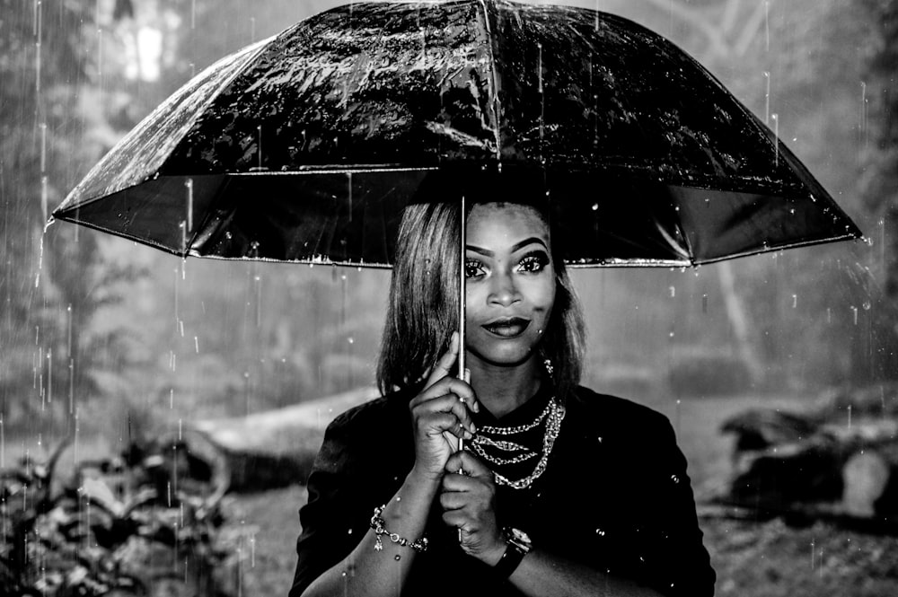 grayscale photography of woman under umbrella at rainy season
