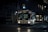 A city bus is captured during the night, illuminated by streetlights and its own interior lighting. The bus is on route 6A, heading to Bay and Dupont. The scene is set on a city street with minimal traffic and the urban landscape is partially visible with buildings in the background.