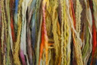 Close-up of hands carefully sorting colorful yarn waste in a bright factory setting.