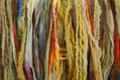 A close-up of colorful yarns and materials for rug making.