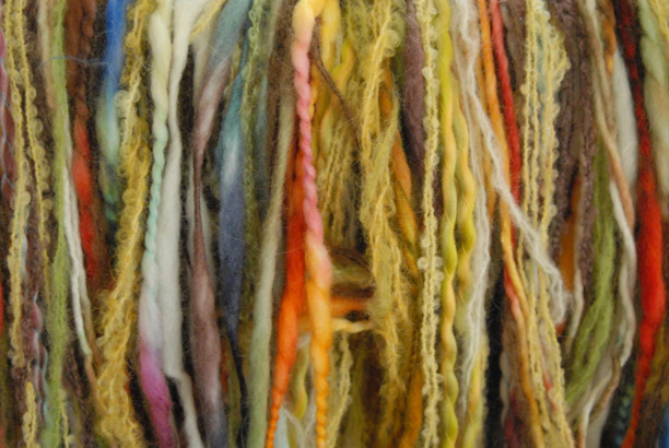 Close-up of hands carefully sorting colorful yarn waste in a bright factory setting.