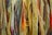 A close-up of various strands of yarn in multiple colors, including shades of yellow, green, red, blue, and brown. The yarn is textured, with some strands appearing thick and others thin, creating a layered and vibrant appearance.