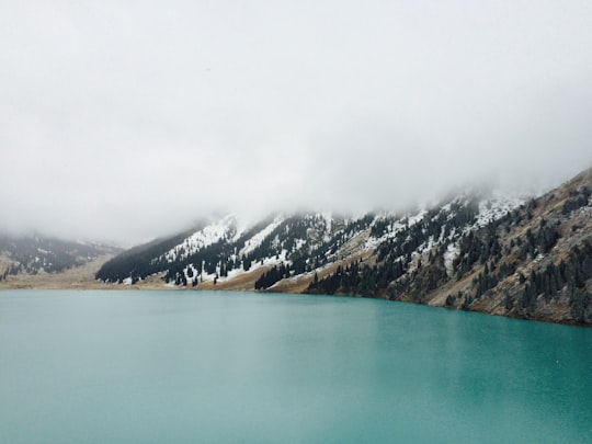 body of water within mountain range during fog in Ile-Alatau National Park Kazakhstan