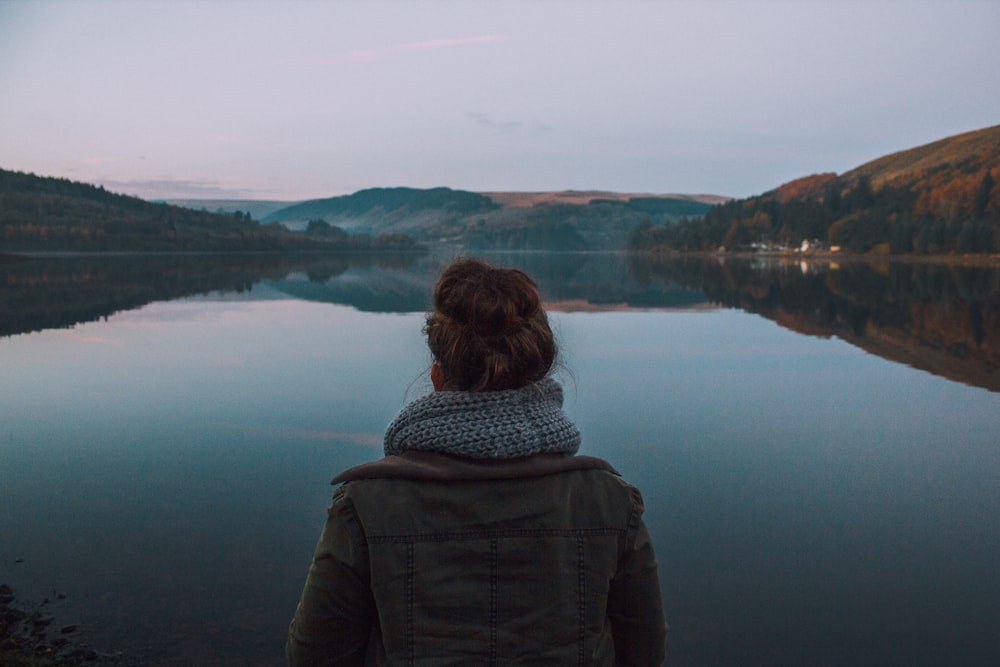 femme debout devant le plan d’eau à l’aube