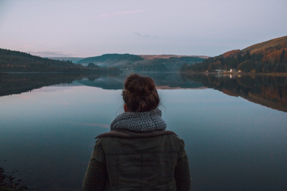 woman standing in front of body of water during dawn