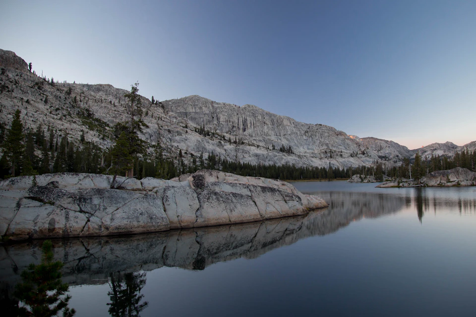 Serene mountain lake surrounded by lush green trees and rocky shoreline with calm waters