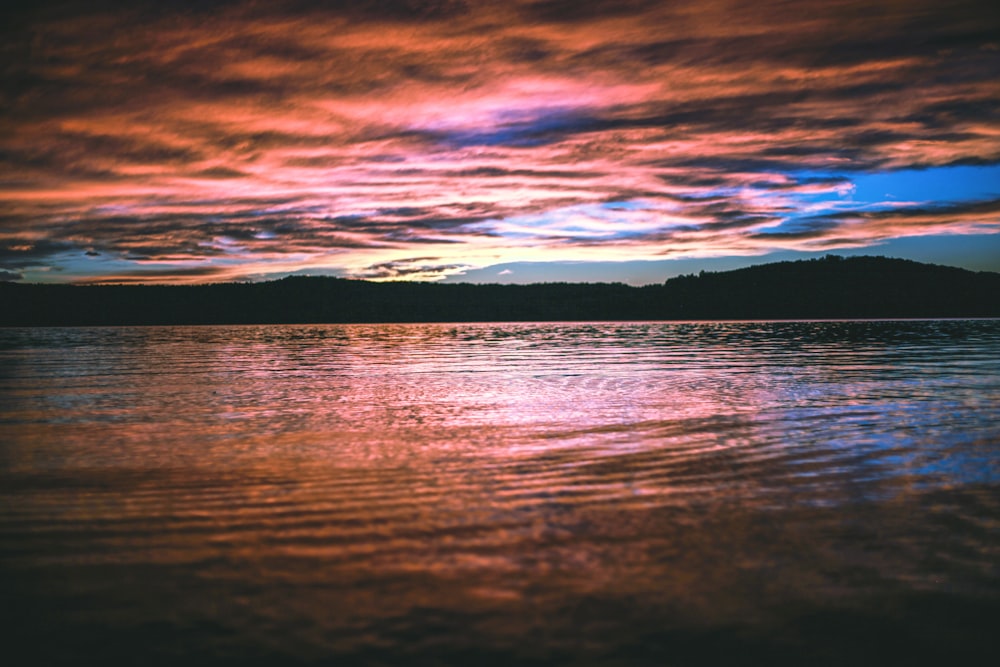 reflective photography of mountain and body of water