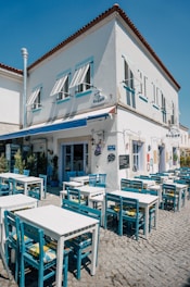 A charming outdoor view of Tattershall Castle Cafe with rustic wooden tables and blooming flower pots under a bright blue sky.